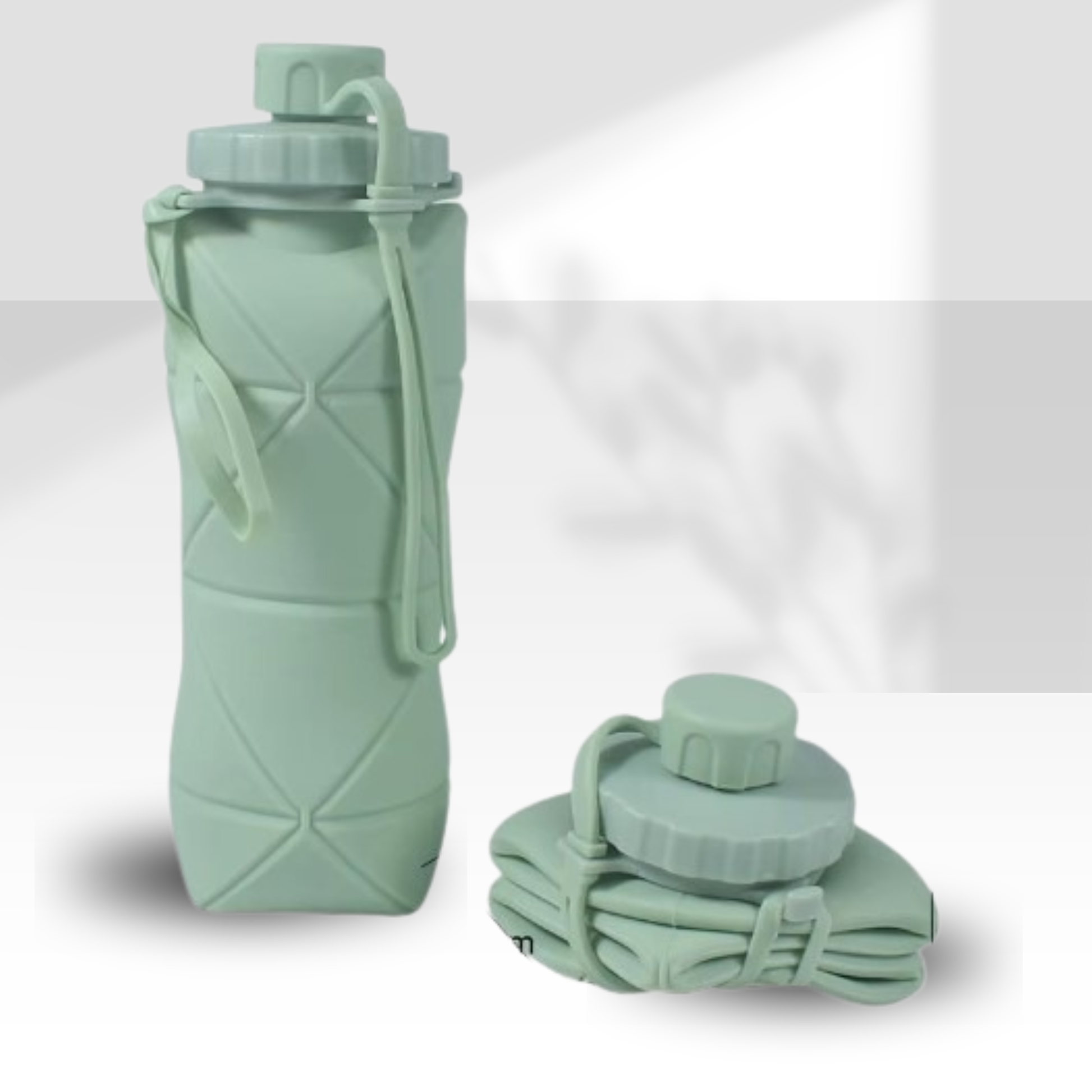 A light sage green collapsible water bottle with a matching carrying strap, shown standing upright next to its folded state on a clean, light gray background.