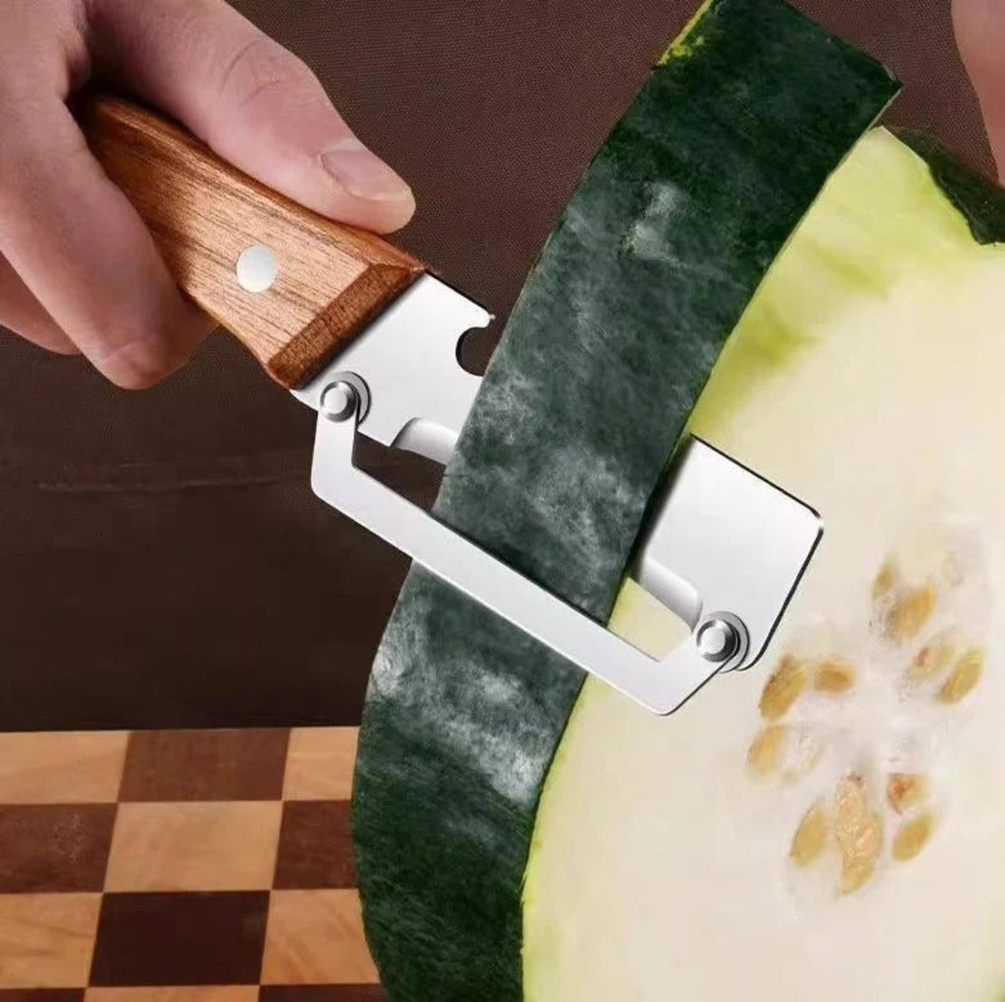 Person using a melon baller to scoop out a round piece ofmelon on a checkered surface.